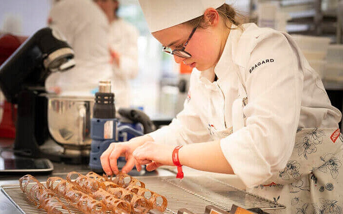 Candidat présentant une création complexe lors d'un concours de pâtisserie